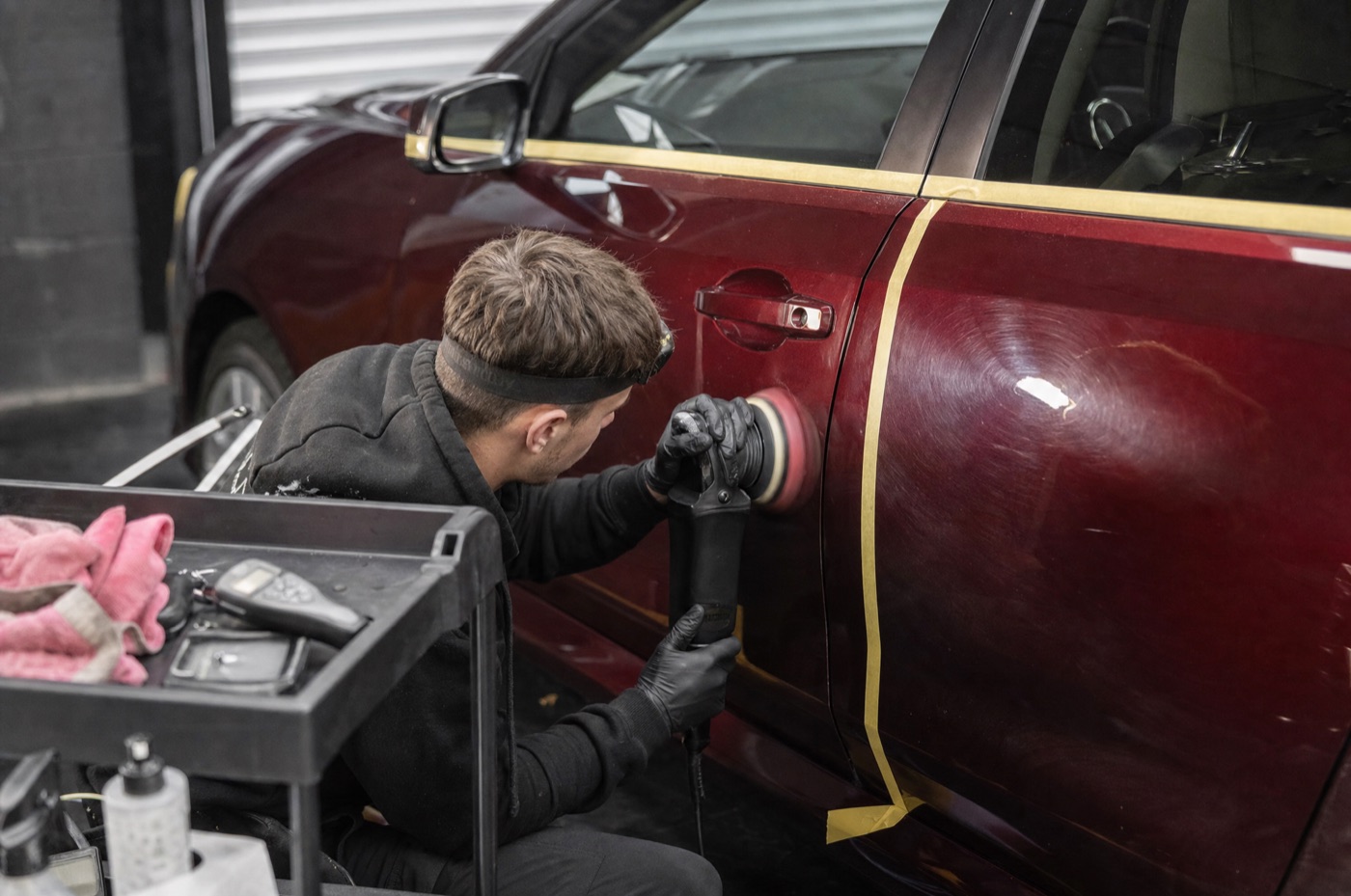 A detailer using a dual-action polisher to correct swirl marks on a car's bonnet